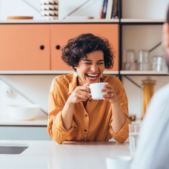 une femme boit un café en riant